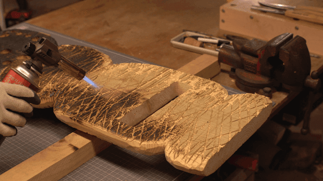 작업실에서 토치로 나무를 태우는 장면