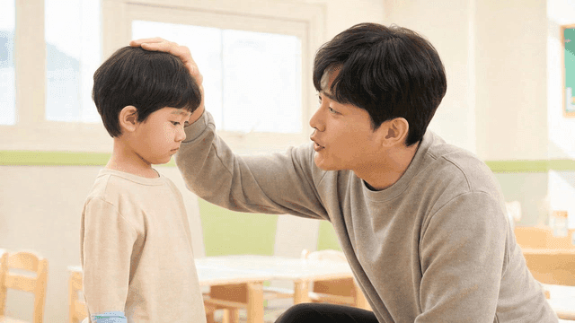 Teacher gently stroking child's head at kindergarten