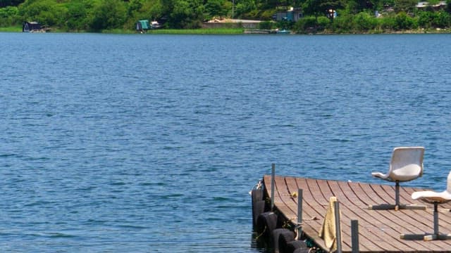 Quiet wooden deck with empty chairs on a serene lake