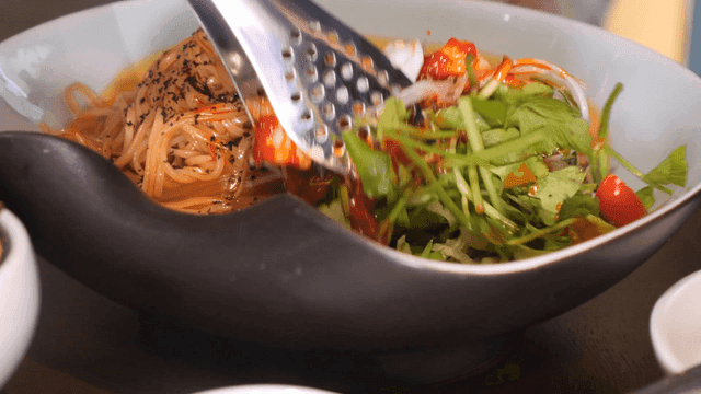 Mixing noodles with fresh vegetables