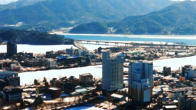 Snow-covered cityscape with river and mountains