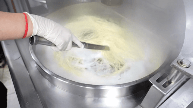 Noodles being stirred in a steaming pot