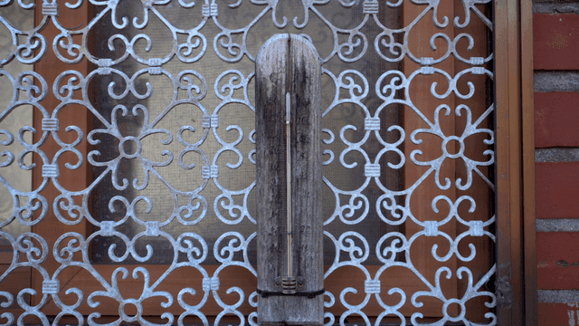 금속 격자로 장식된 창문 앞 나무 조각품