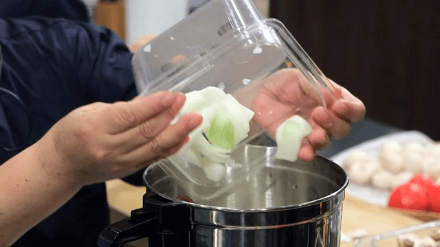 Chopped onions being added to a pot