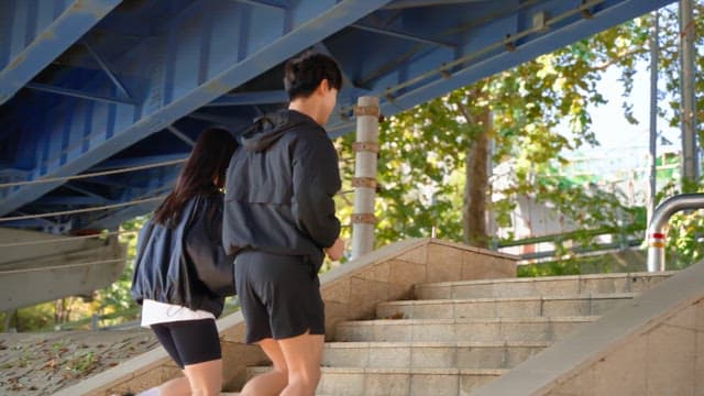 Two people jogging under a bridge