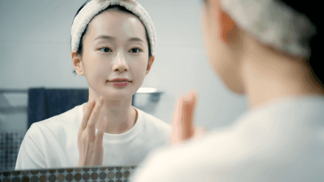 Woman applying skincare in front of mirror
