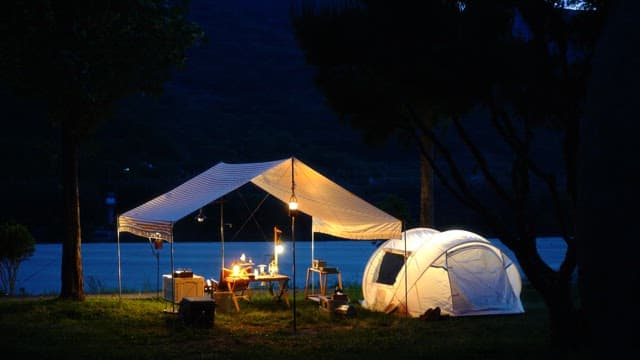 Evening campsite by river illuminated with soft lighting