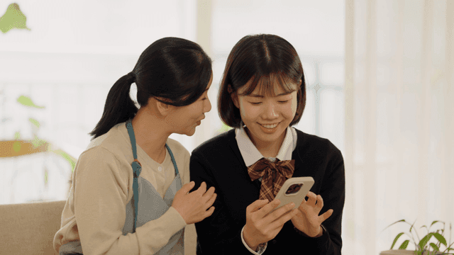 Mother and daughter laughing together and looking at their smartphones
