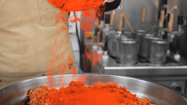 Chef pouring red chili powder into bowl