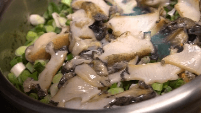 솥에 담긴 전복을 토치로 그을리기