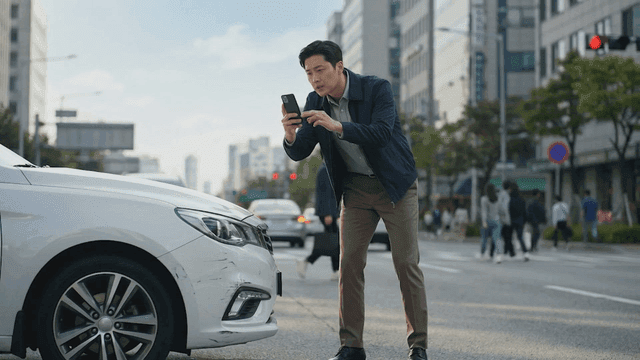 Man filming vehicle damage on road