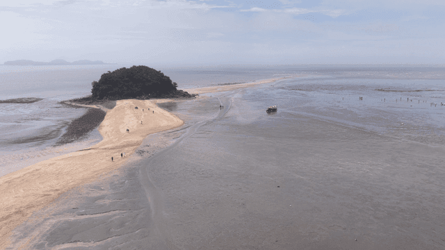Sandy beach where people walk, connected by small islands