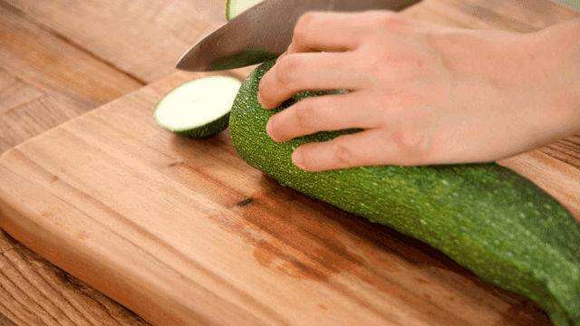 Cutting zucchini on wooden cutting board