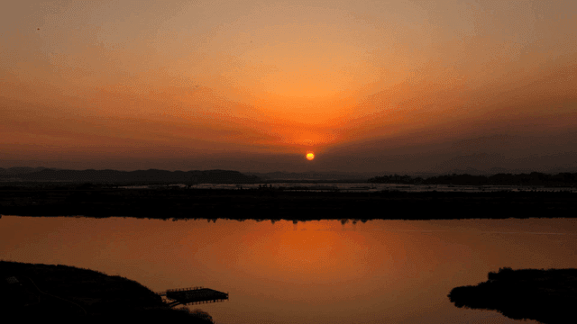 Sunset over calm river reflecting sky