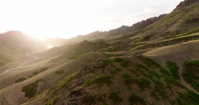 햇빛을 받으며 산 위에 서 있는 사람