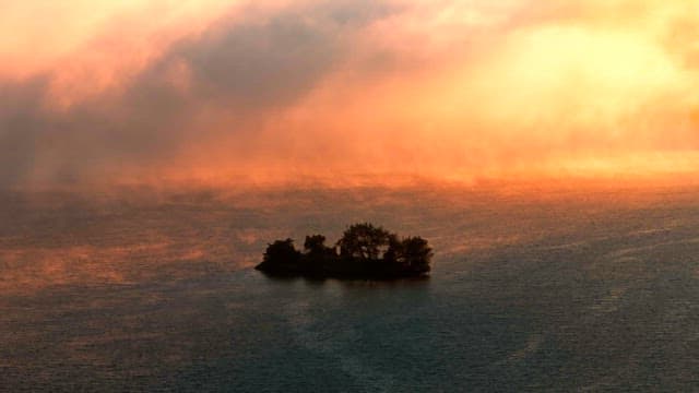 Small island surrounded by mist at sunset