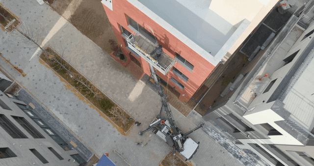Workers maintaining buildings with crane lifts