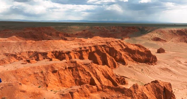 Expansive red desert landscape under cloudy sky