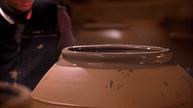 큰 도자기에 붓으로 칠을 하는 사람