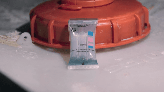 약물 테스트 키트를 들고 있는 장갑 낀 손