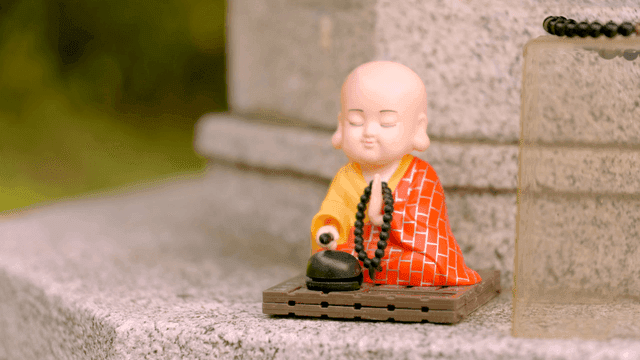 Souvenir of small monk holding prayer beads