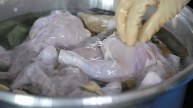 Scene of adding raw chicken to a pot of water
