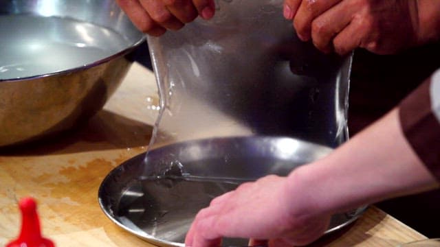 Chef removing cooked starch batter from a tray