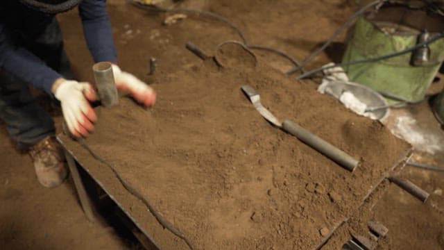 Worker shaping sand mold in a workshop