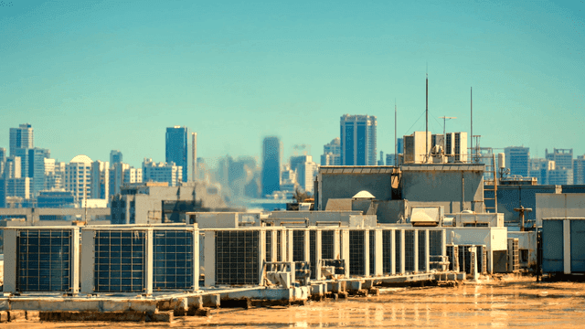 City skyline and rooftop with air conditioner outdoor unit spewing hot air.