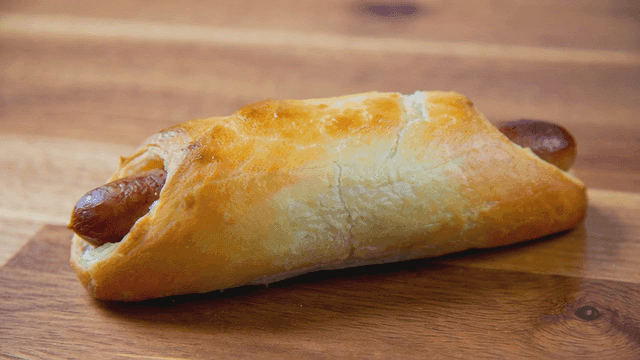 Freshly baked sausage rolls on wooden cutting board