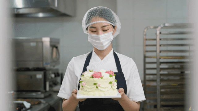 A baker holding a beautifully decorated cake