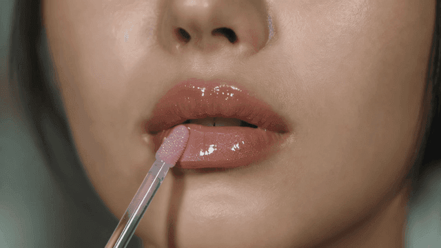 Woman applying lip gloss to her lips