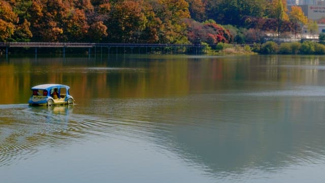 Small boat cruising on a serene autumn lake surrounded by trees