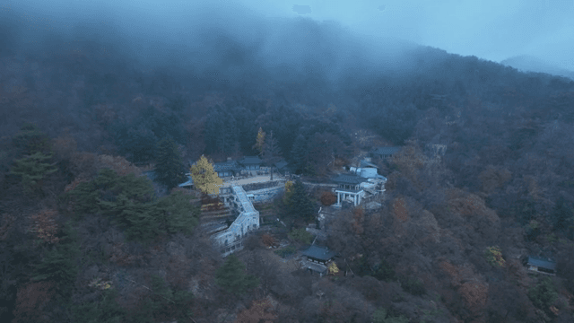 Misty mountain landscape with a distant hanok