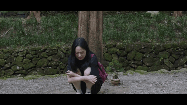 Woman sitting in front of a tree and crying