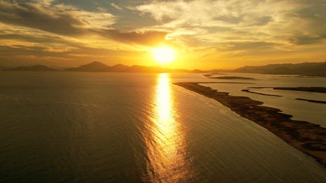 멀리 산이 보이는 고요한 바다에서의 일몰