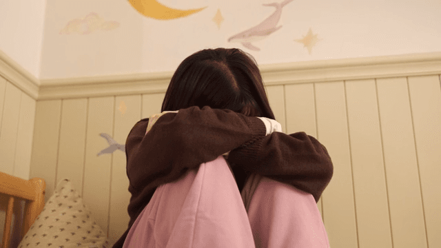 Young woman looking frustrated while looking at her smartphone in her room