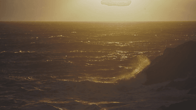 Sunset over the ocean with waves crashing