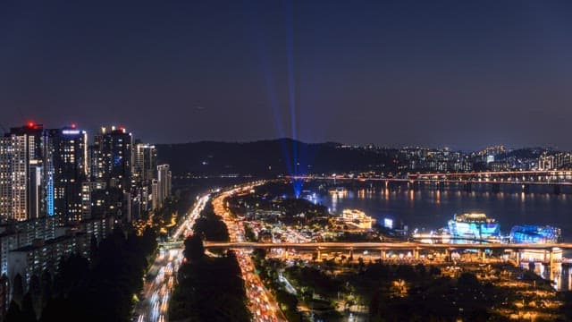 강변을 따라 빛나는 도로와 밝게 빛나는 건물들이 있는 활기찬 도시의 야경