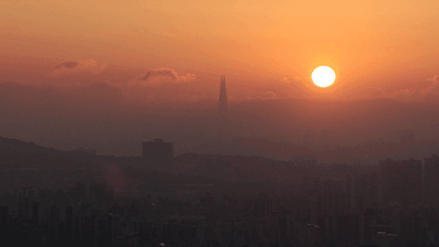 구름과 함께 도시 스카이라인 위로 떠오르는 해