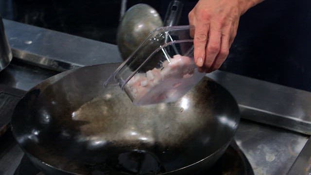 Diced meat being fried in a hot wok