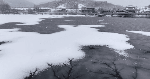 Snow-covered lake with distant buildings
