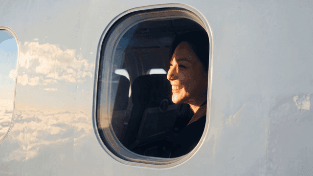 Woman smiling while looking out airplane window