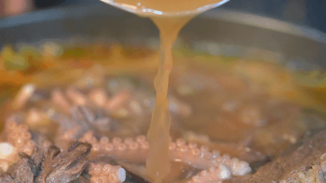 Live octopus and short rib hot pot with broth poured from ladle