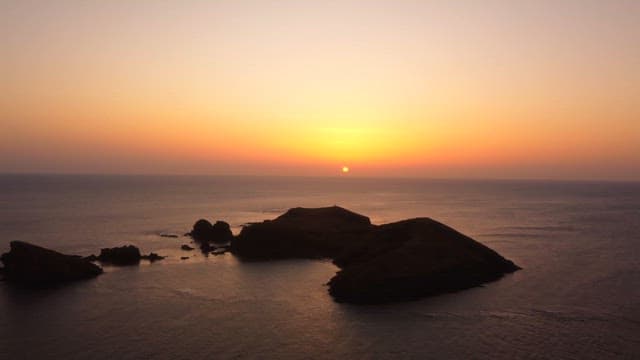 섬이 있는 고요한 바다 위의 일몰