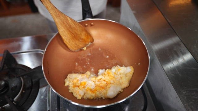 Cooking scrambled eggs with green onions in frying pan