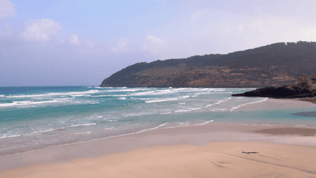 Quiet beach with waves and distant hills