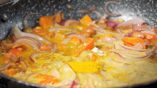 팬에서 끓고있는 커리 가루가 들어있는 각종 야채