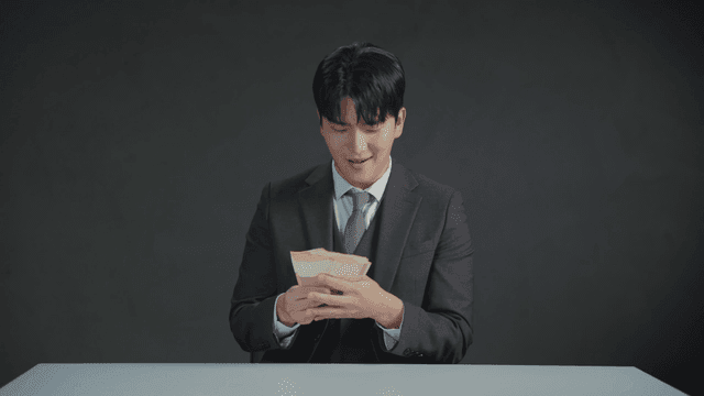 만족스러운 표정으로 돈을 세는 정장 입은 남자
