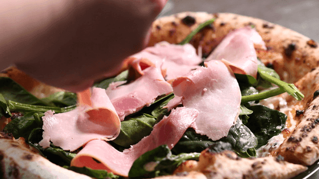 Freshly baked pizza with ham and spinach